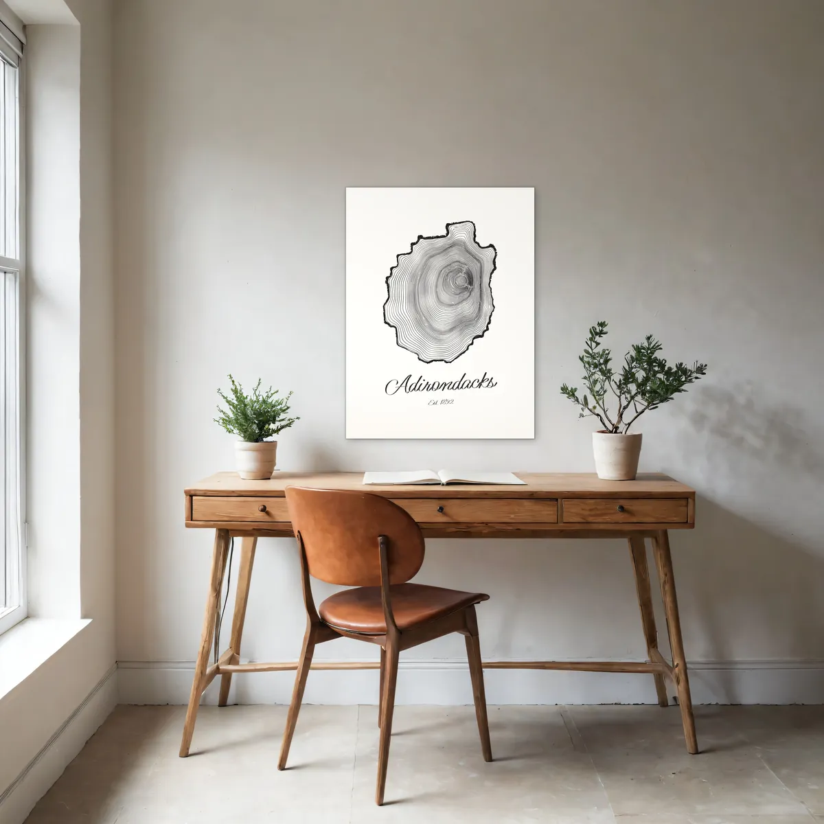 An 18 by 24 inch Ring & Ridge poster of Adirondack tree rings on a white wall above an oak desk. Shown in a rendered room.