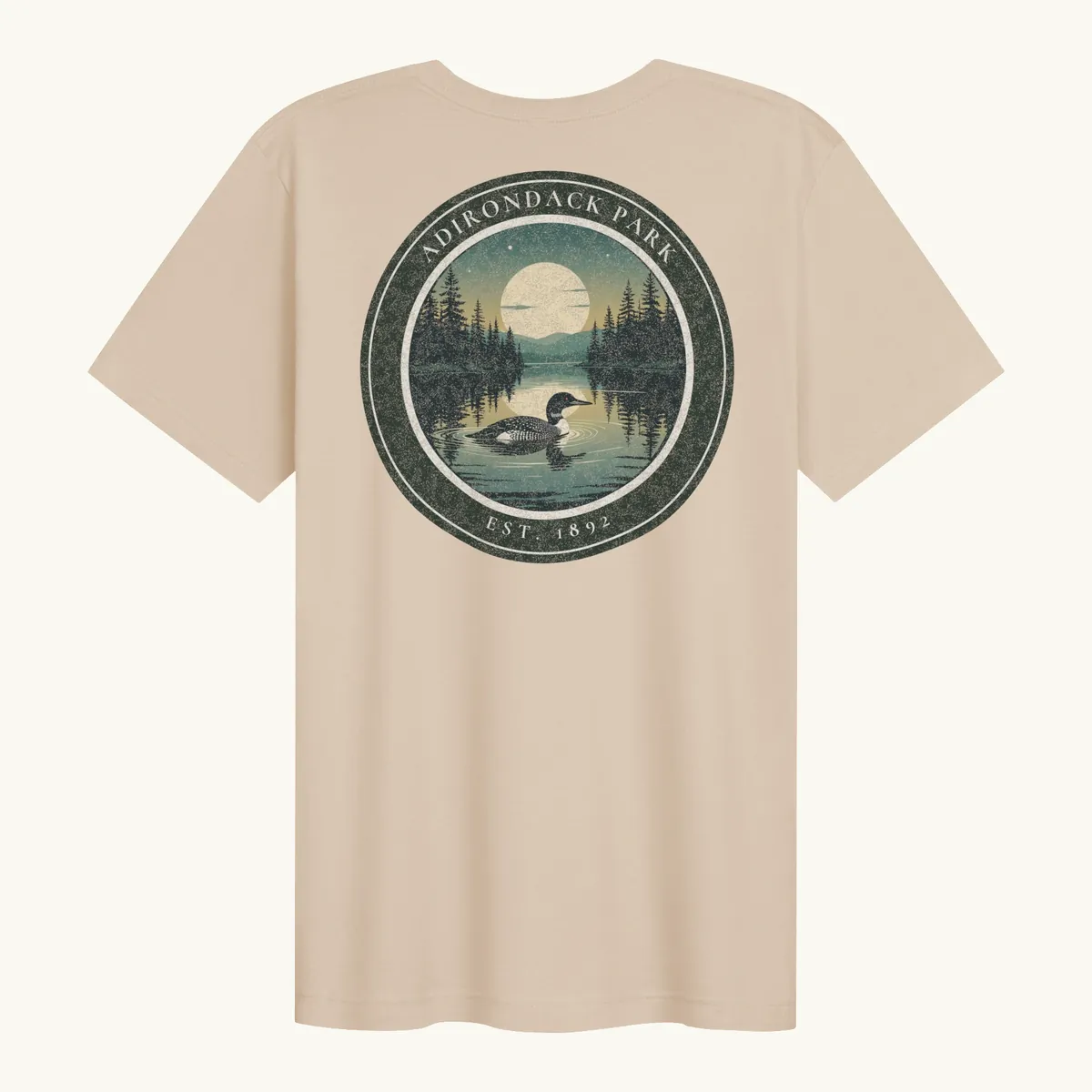 Loon at Night Tee in Soft Cream, back: a loon on a moonlit Adirondack lake in a round badge, Adirondack Park, Est. 1892.