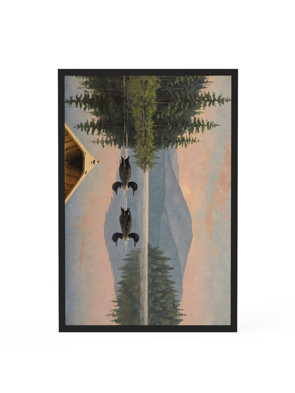 Loon Pair at Sunrise as a 24 by 36 inch framed print in a black frame: two common loons swimming side by side across a still Adirondack lake at sunrise, seen from the bow of a wooden canoe, with spruce shores, a blue mountain and a peach-pink sky doubled in the water, in soft, traditional oil brushwork.