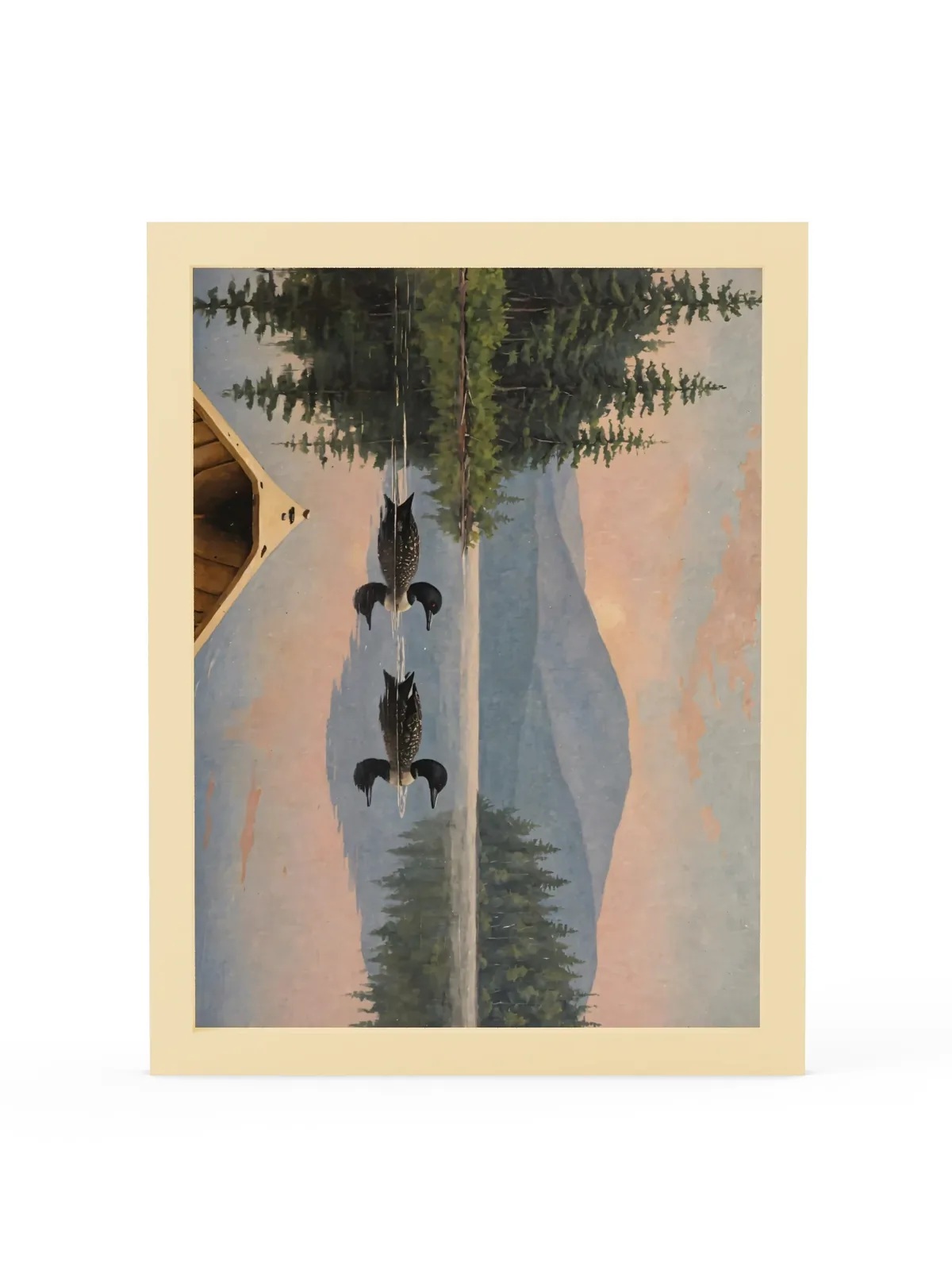 Loon Pair at Sunrise as a 12 by 16 inch framed print in a natural wood frame: two common loons swimming side by side across a still Adirondack lake at sunrise, seen from the bow of a wooden canoe, with spruce shores, a blue mountain and a peach-pink sky doubled in the water, in soft, traditional oil brushwork.