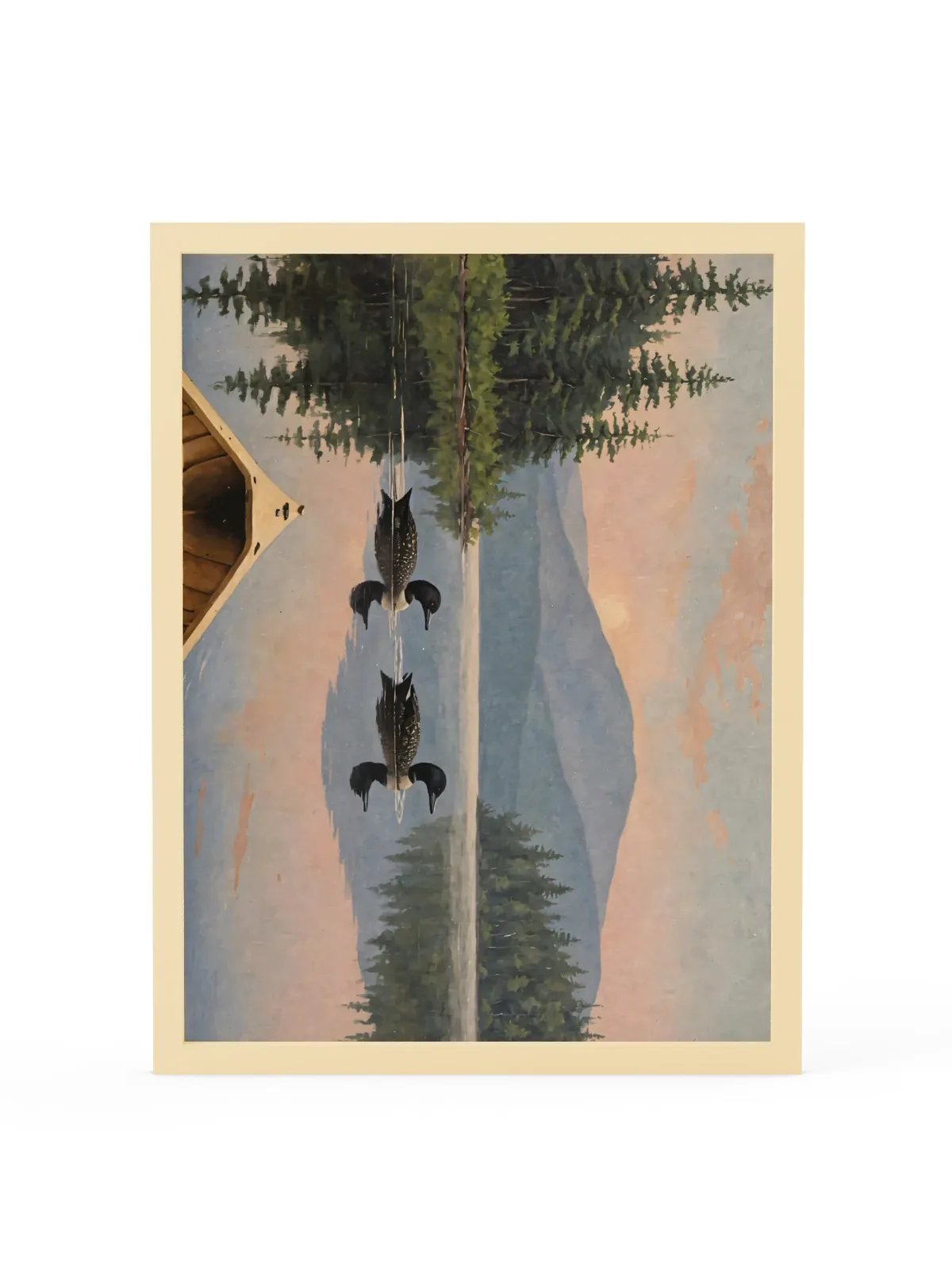 Loon Pair at Sunrise as an 18 by 24 inch framed print in a natural wood frame: two common loons swimming side by side across a still Adirondack lake at sunrise, seen from the bow of a wooden canoe, with spruce shores, a blue mountain and a peach-pink sky doubled in the water, in soft, traditional oil brushwork.