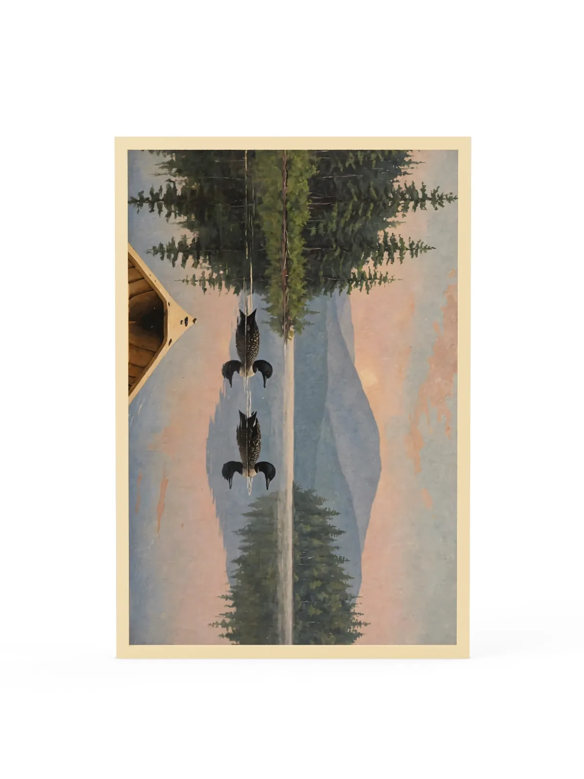 Loon Pair at Sunrise as a 24 by 36 inch framed print in a natural wood frame: two common loons swimming side by side across a still Adirondack lake at sunrise, seen from the bow of a wooden canoe, with spruce shores, a blue mountain and a peach-pink sky doubled in the water, in soft, traditional oil brushwork.