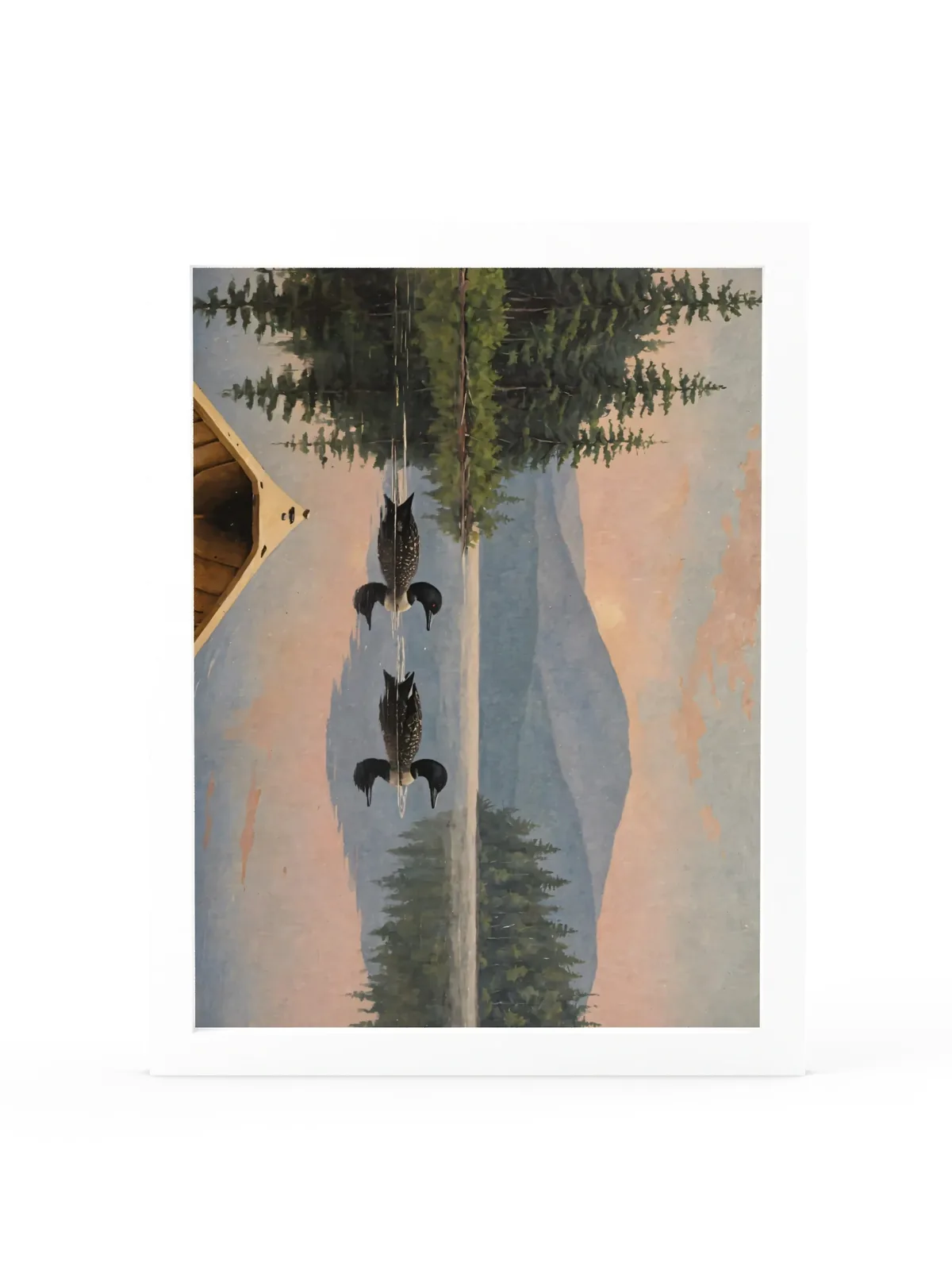 Loon Pair at Sunrise as a 12 by 16 inch framed print in a white frame: two common loons swimming side by side across a still Adirondack lake at sunrise, seen from the bow of a wooden canoe, with spruce shores, a blue mountain and a peach-pink sky doubled in the water, in soft, traditional oil brushwork.