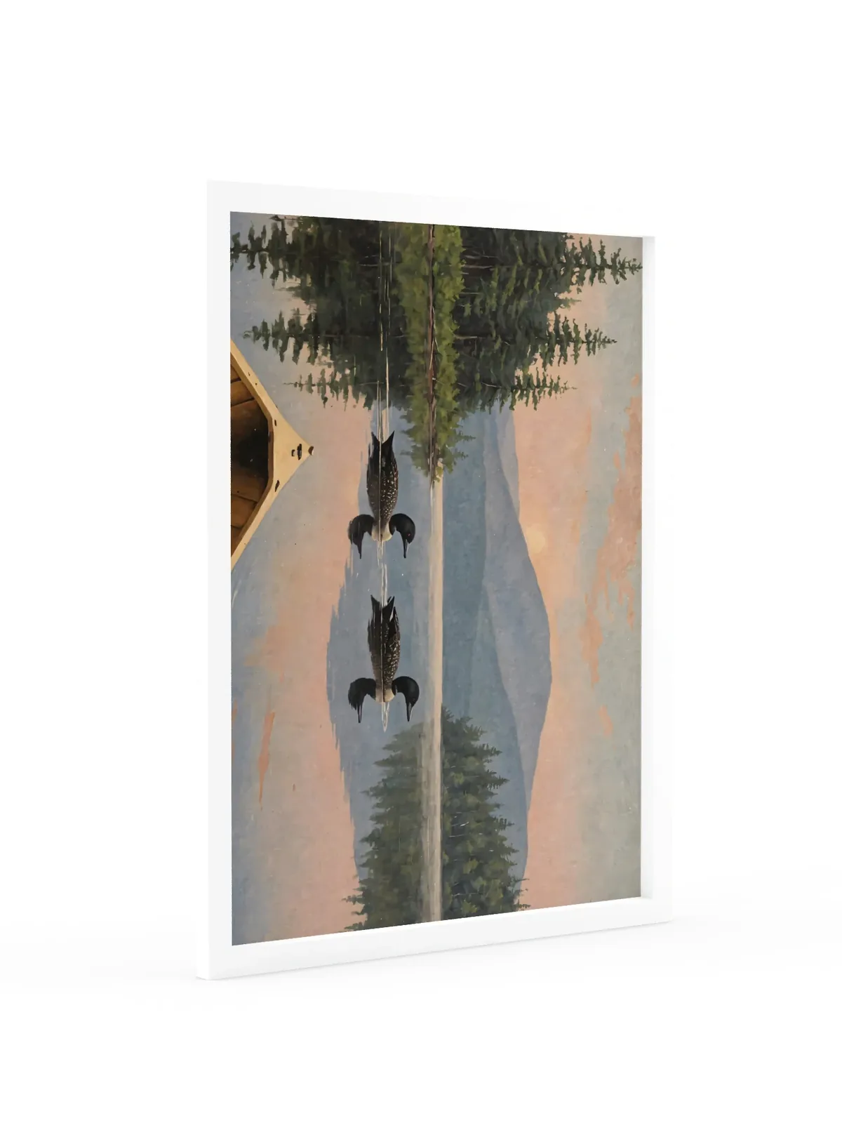 Loon Pair at Sunrise as an 18 by 24 inch framed print in a white frame: two common loons swimming side by side across a still Adirondack lake at sunrise, seen from the bow of a wooden canoe, with spruce shores, a blue mountain and a peach-pink sky doubled in the water, in soft, traditional oil brushwork.