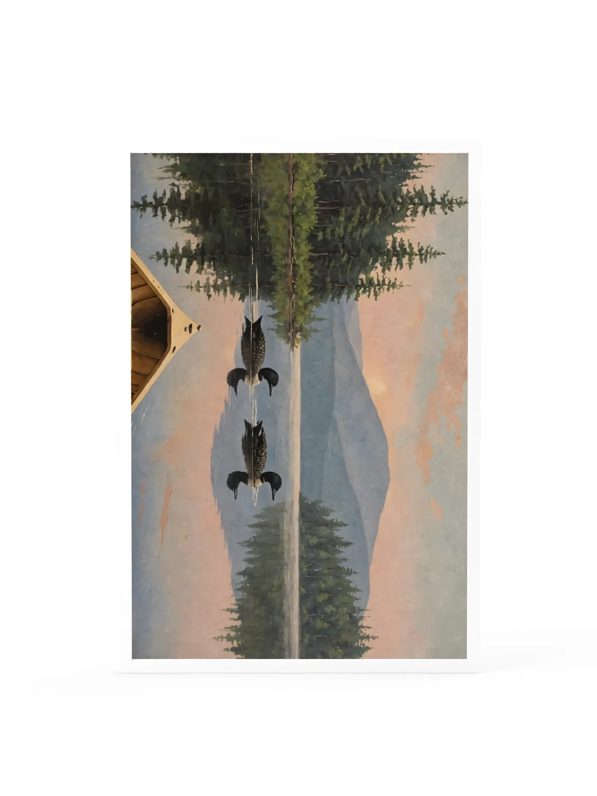Loon Pair at Sunrise as a 24 by 36 inch framed print in a white frame: two common loons swimming side by side across a still Adirondack lake at sunrise, seen from the bow of a wooden canoe, with spruce shores, a blue mountain and a peach-pink sky doubled in the water, in soft, traditional oil brushwork.